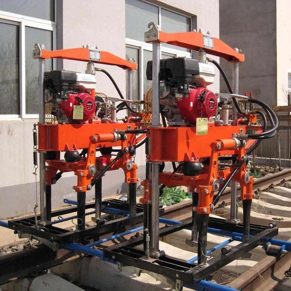 Technician operating a hydraulic rail tamping machine during track maintenance Technician operating a hydraulic rail tamping machine during track maintenance